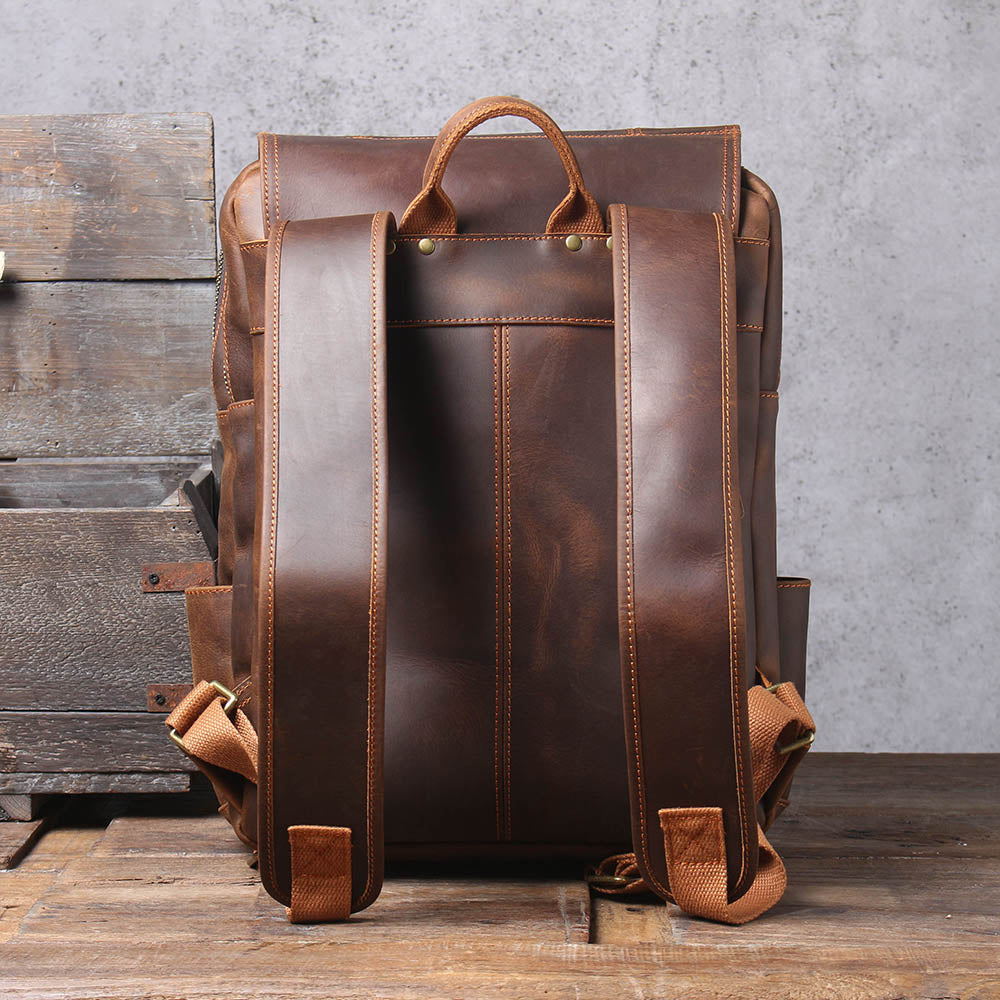 back of the brown leather rucksack: plain leather panel, padded straps and top handle