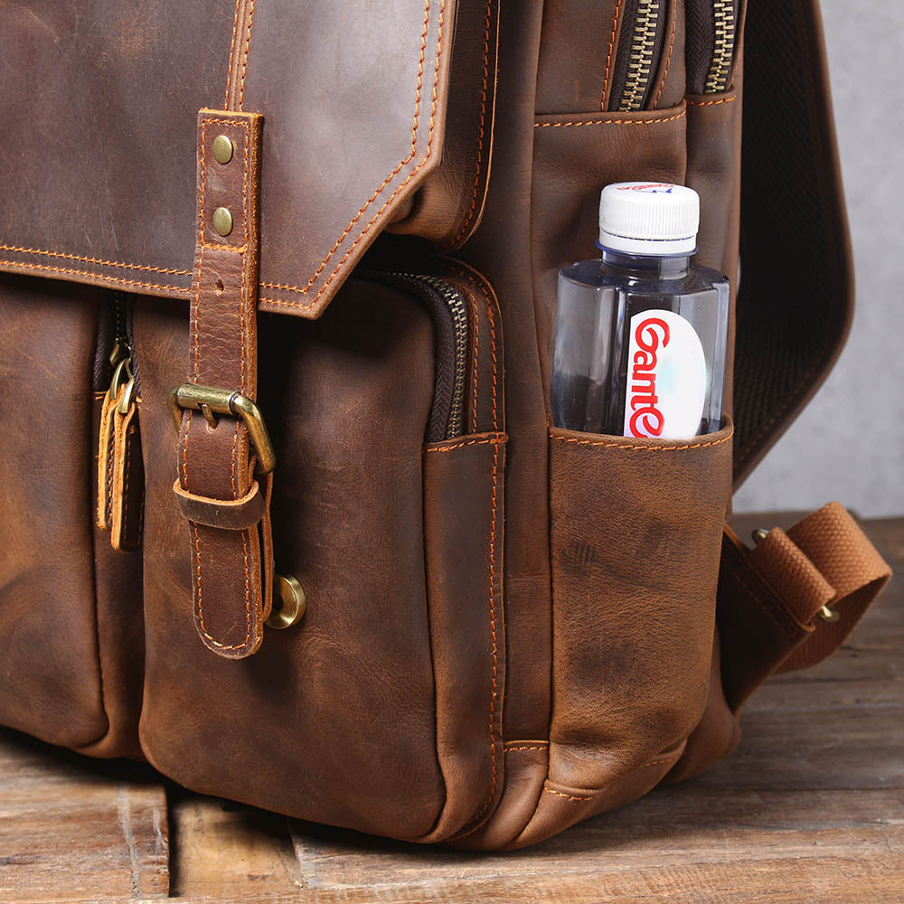 side pocket of the brown leather rucksack holding a water bottle