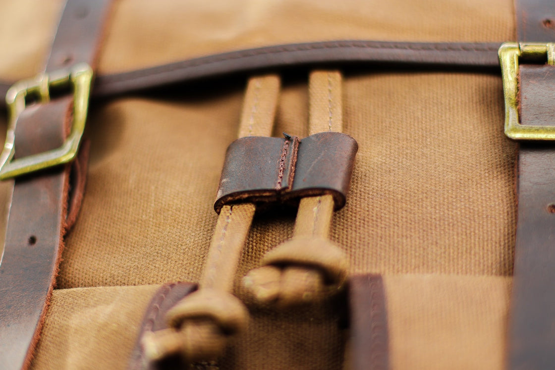 Detail of the canvas-cord drawstring closure with leather barrel keeper on the khaki Calgary rucksack