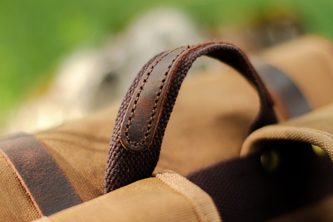 Macro of the cotton-wrapped dark leather grab handle with reinforced canvas anchor on the top of the Calgary backpack