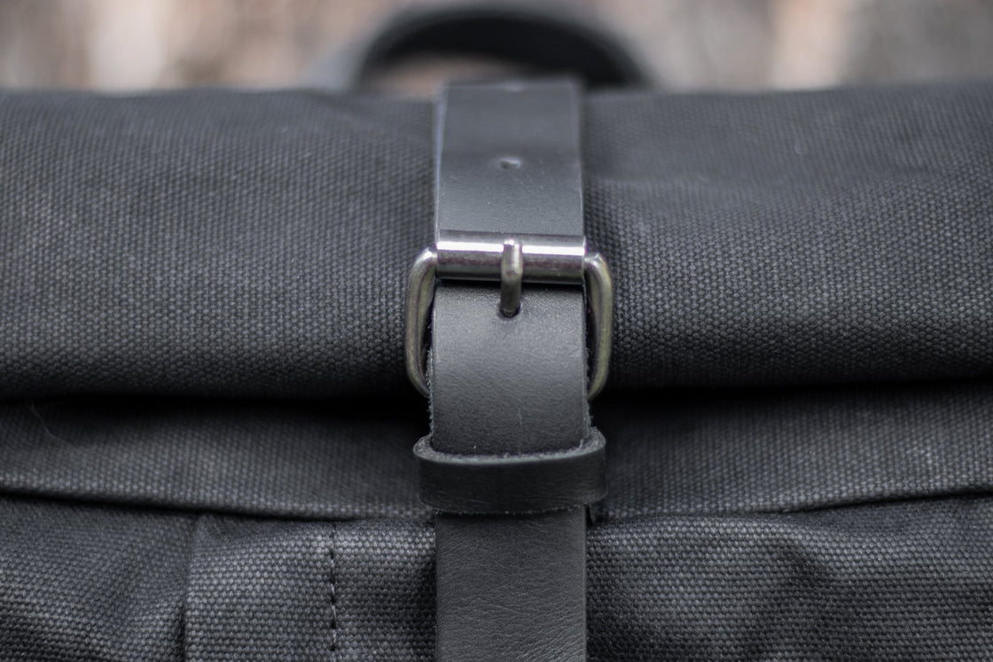 Black Gstaad classic biker canvas back pack with rolltop closure, leather strap and brass buckle