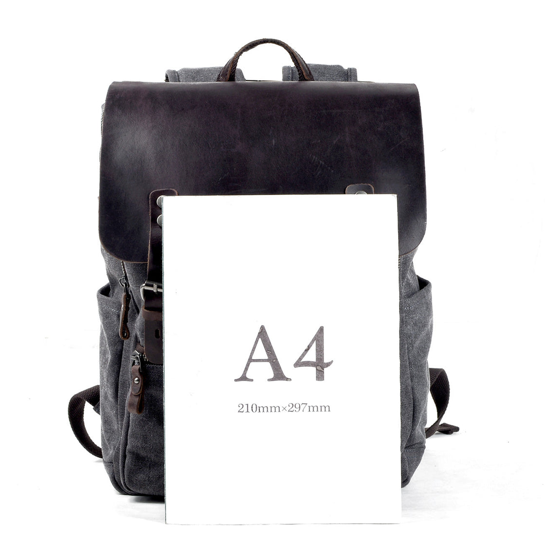 Dark grey Milan canvas backpack beside an A4 sheet for size reference, showing document and laptop-friendly proportions