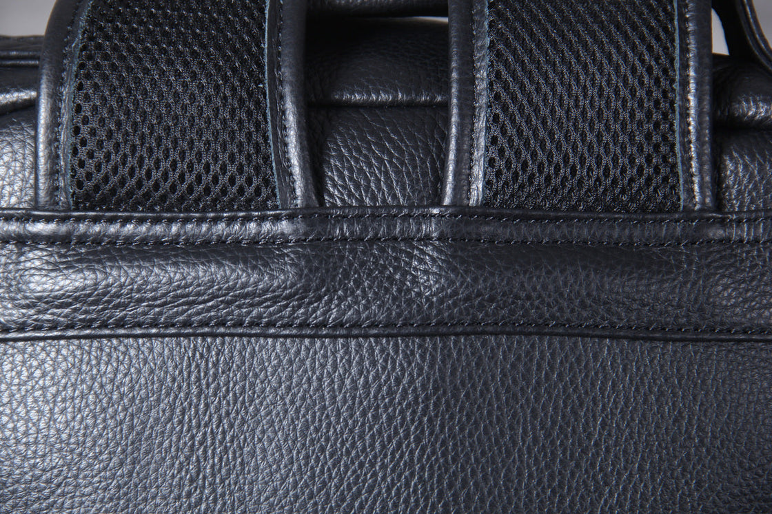 tablet and magazine sliding into the two front zip pockets of the leather laptop backpack