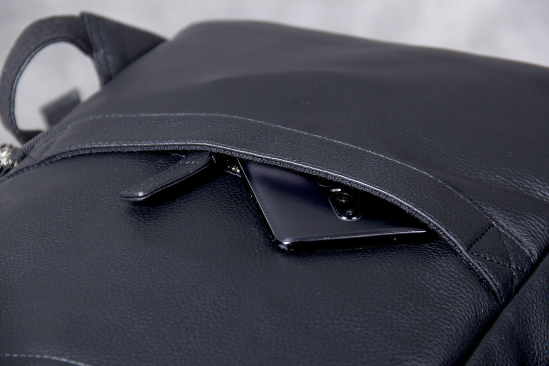 fingers pinching the pebbled grain of the black cowhide leather