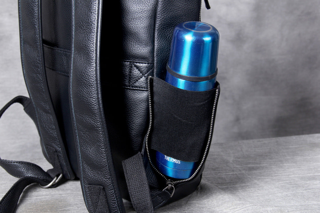 elastic side pocket of the leather backpack holding a thermos flask upright