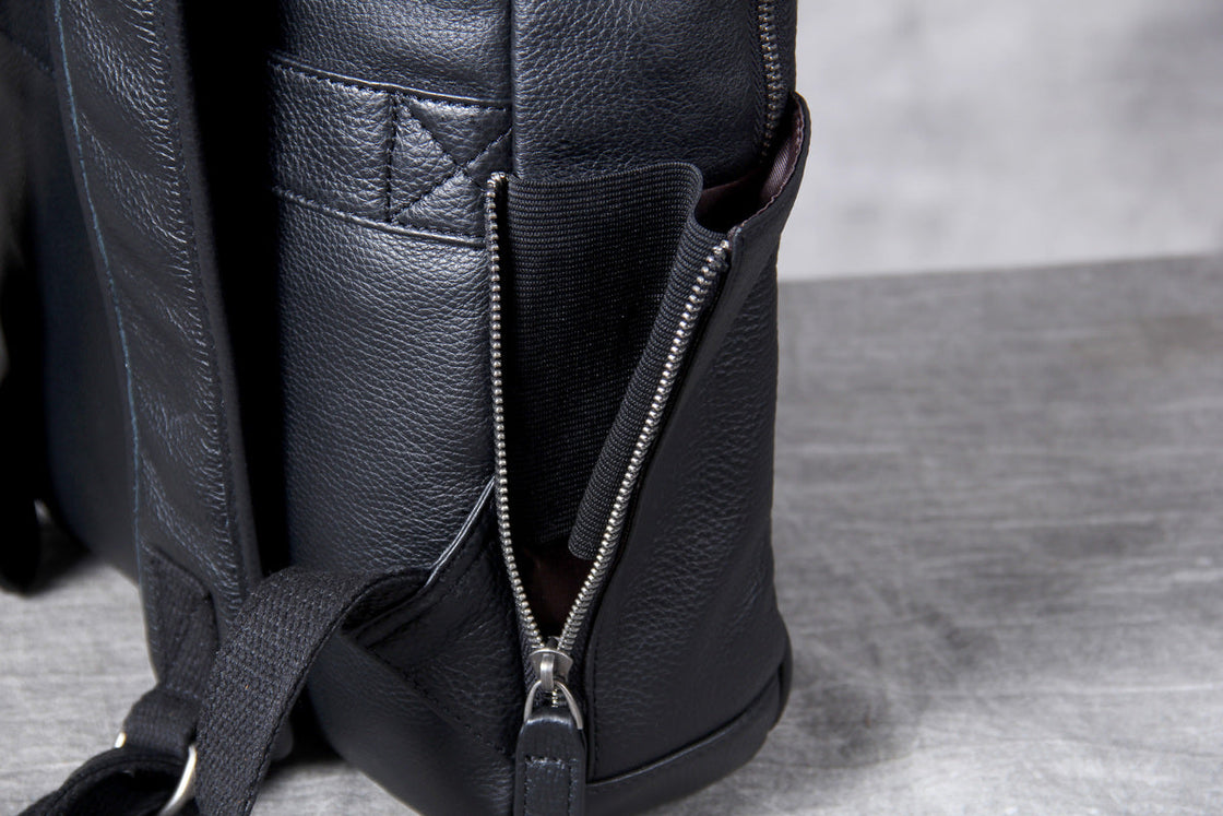 side zip opened to reveal the elastic bottle pocket of the black leather backpack