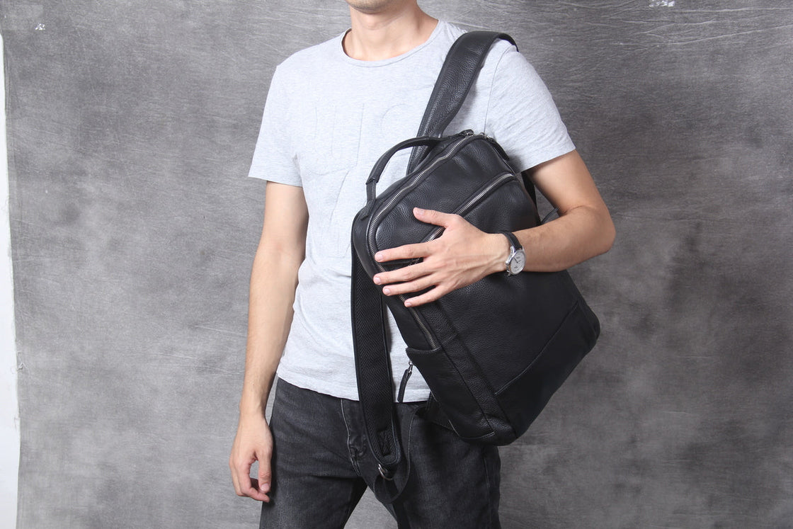black leather backpack carried over one shoulder against the chest