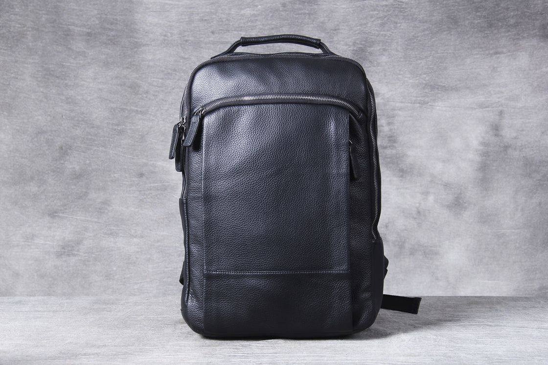 man walking with the black leather laptop backpack in one hand