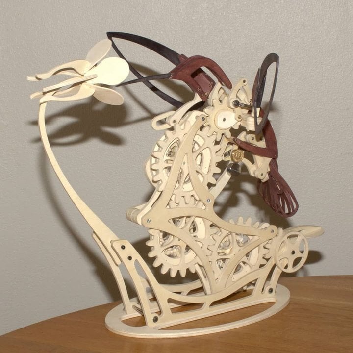 Mechanical model of a horse with gears on a wooden base against a Diyion | Kinetic Hummingbird Sculpture - 3D Wooden Mechanical Puzzle Kit