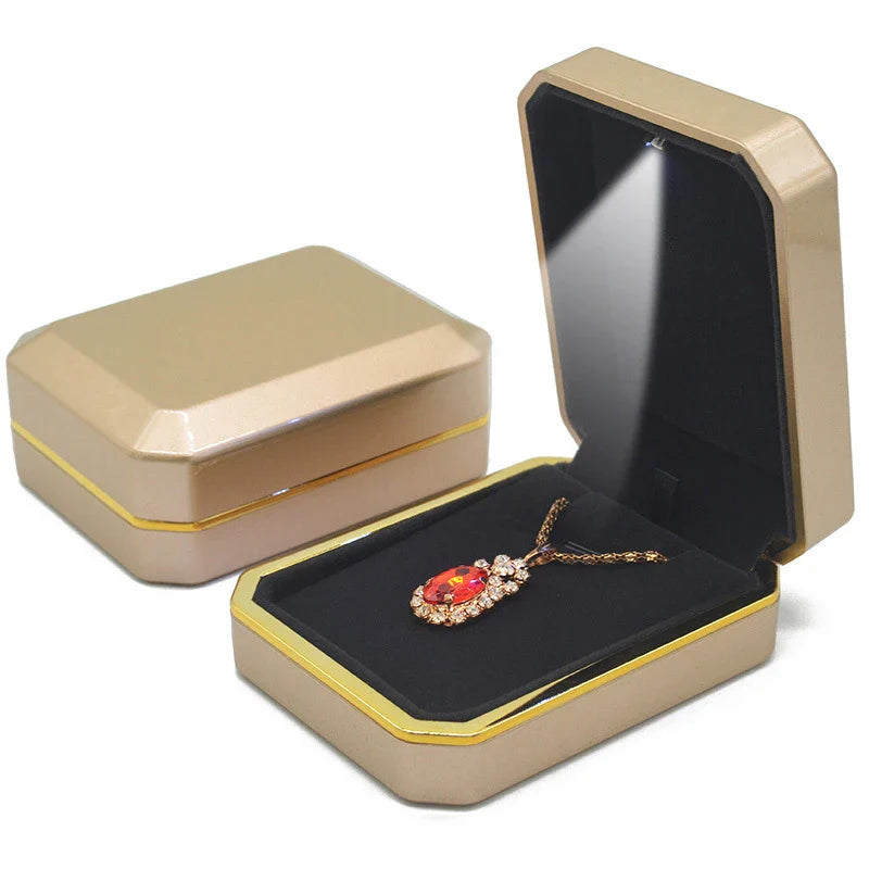 Gold jewelry box with a red gemstone necklace inside LED ring box with automatic light for engagement proposals and wedding jewelry display