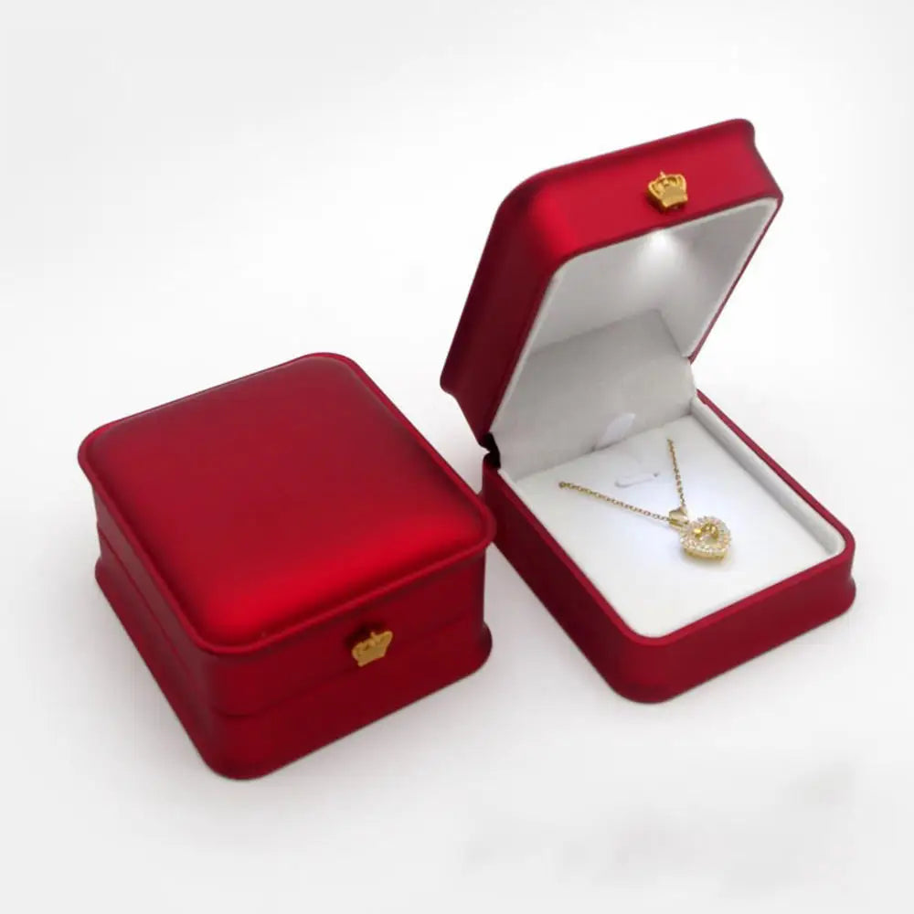 Red jewelry box with a gold necklace inside LED ring box with automatic light for engagement proposals and wedding jewelry display