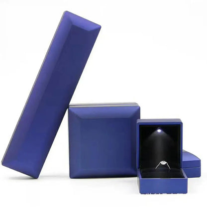 Set of blue jewelry boxes with one open showing a ring inside on a white background