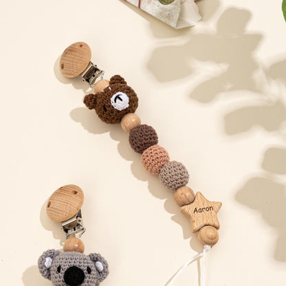 Close up of hand crochet bear pacifier clip with beech wood beads and engraved name star for baby stroller