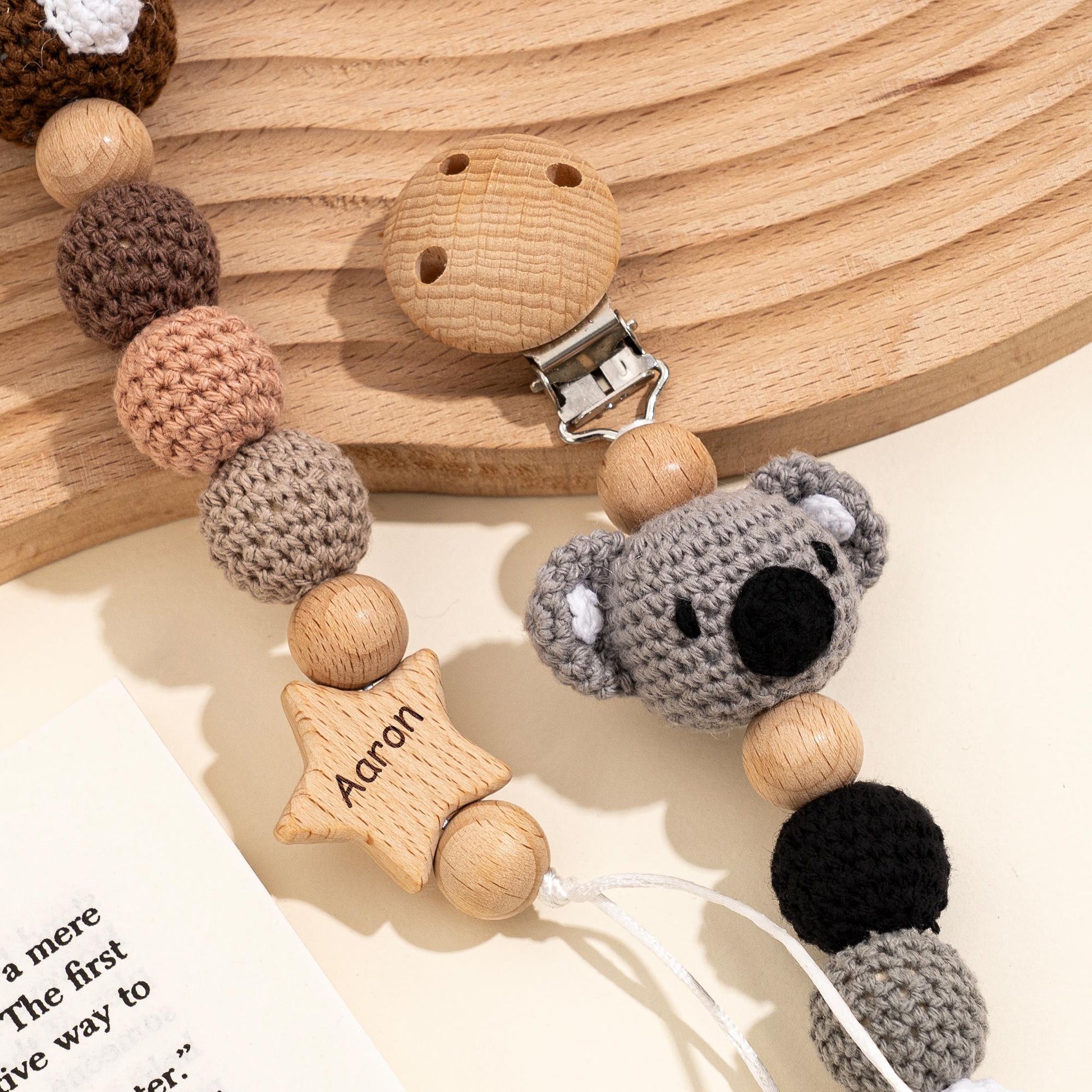 Detail of koala crochet pacifier clip with engraved name star and beech wood beads for newborn baby gift